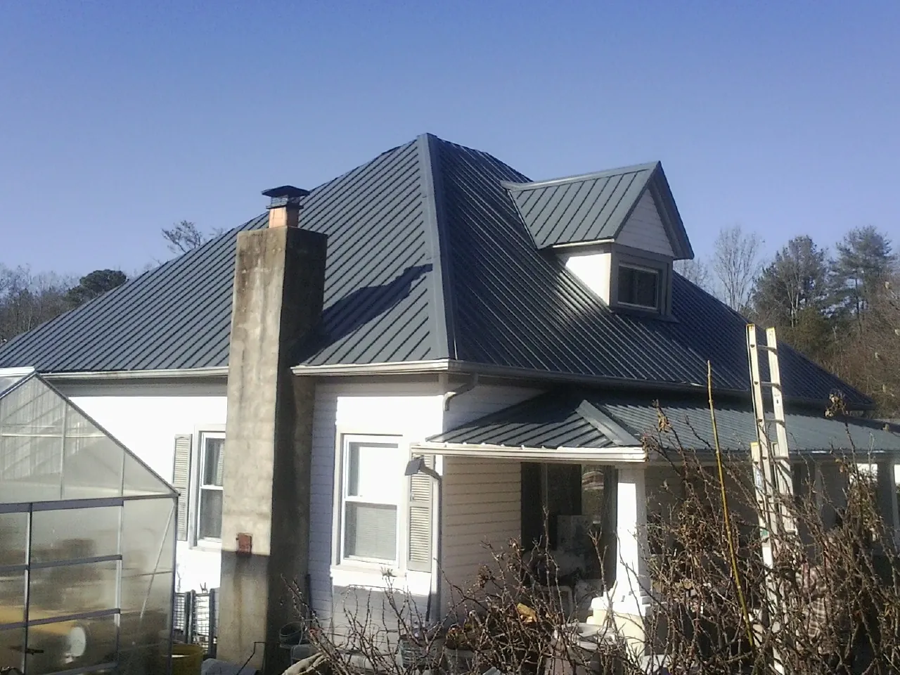 Dark blue standing seam metal roof on a white farmhouse with dormer — Slate & Tile Roof Repair by Roofing Brothers in Lockbourne