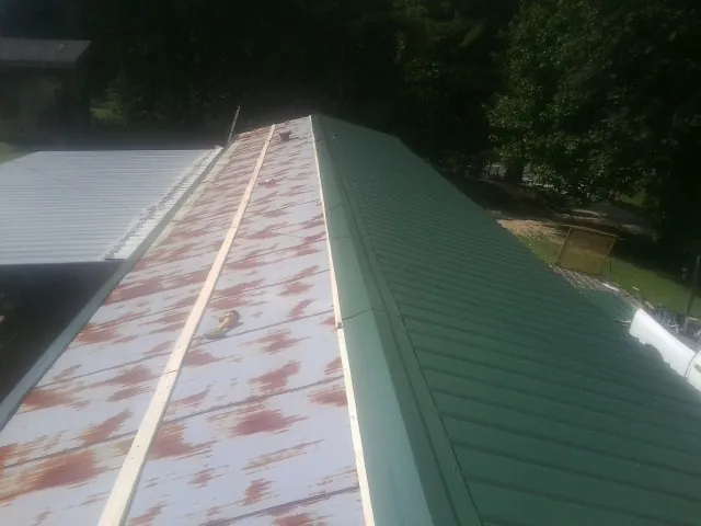 Old rusted panels beside newly installed green metal roofing — Wind Damage Roof Repair by Roofing Brothers in Lockbourne