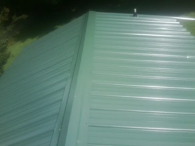 New green metal panels meeting at the ridge of a roof — Flat Roof Repair work by our crew in Lockbourne