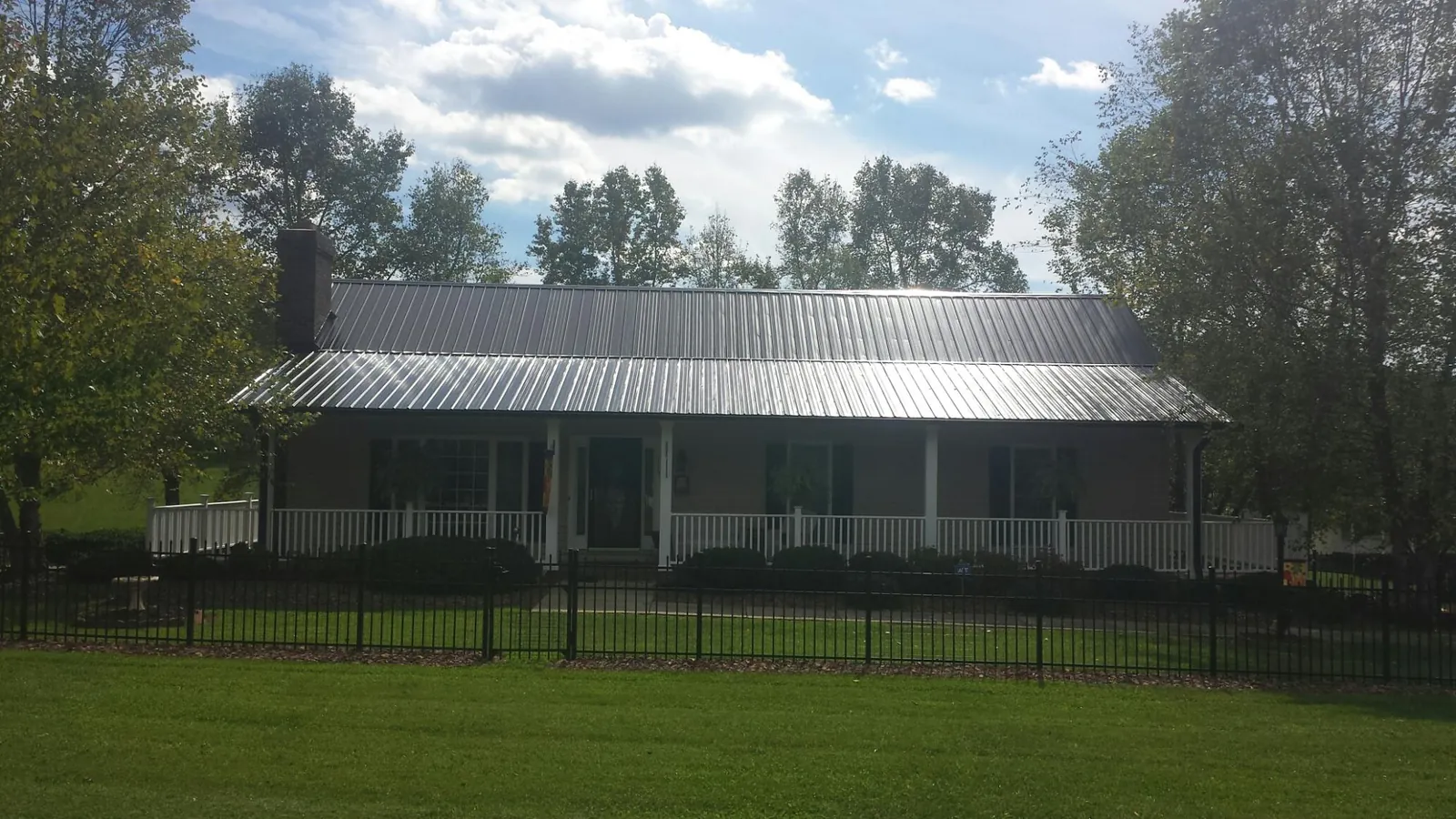 Gray metal roof on a brick ranch with a full width front porch — Gutter Guard Installation work by our crew in Lockbourne